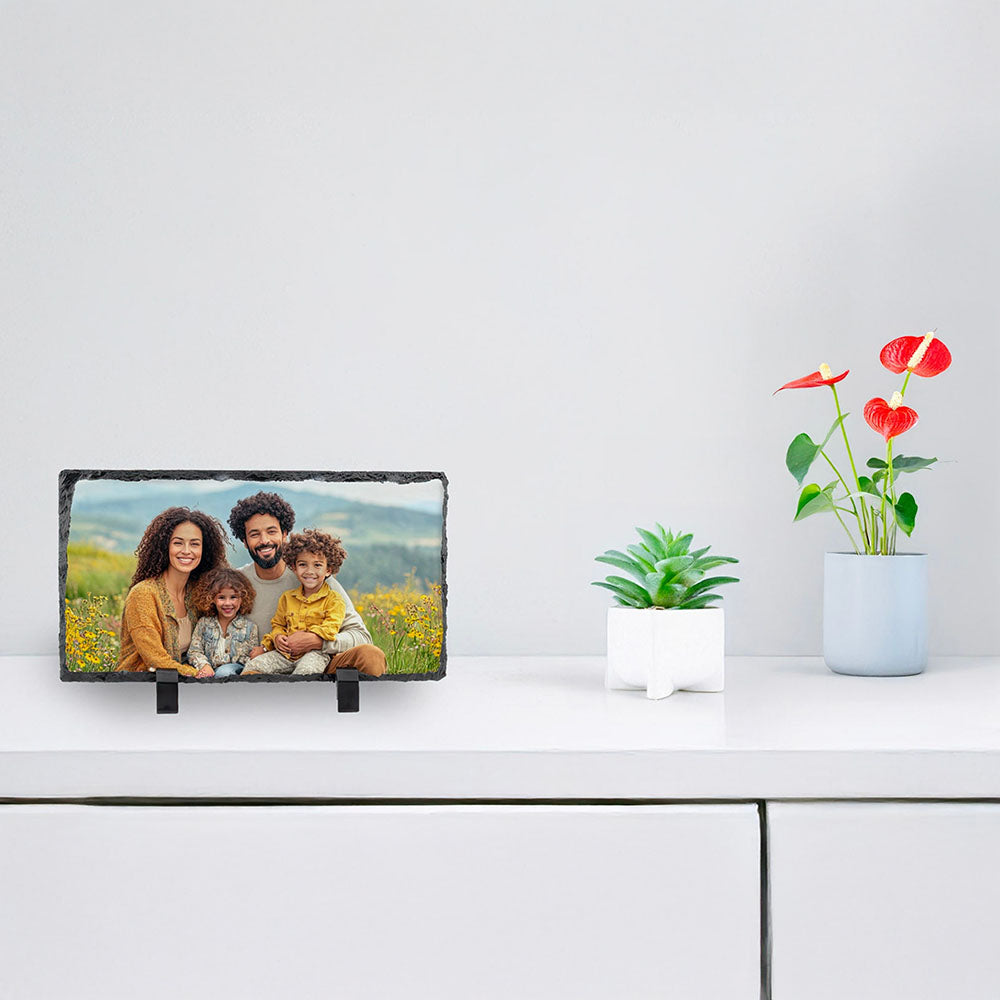 Heart-shaped photo plaque with sunset silhouette, displayed alongside a vase of flowers on a white shelf.