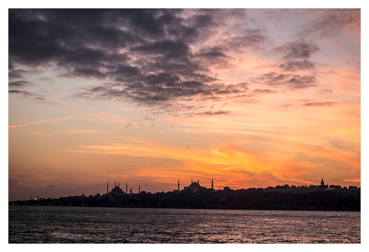 Sunset over Istanbul skyline with Hagia Sophia and Blue Mosque silhouetted, glowing orange and pink sky above the Bosphorus – fine art wall print