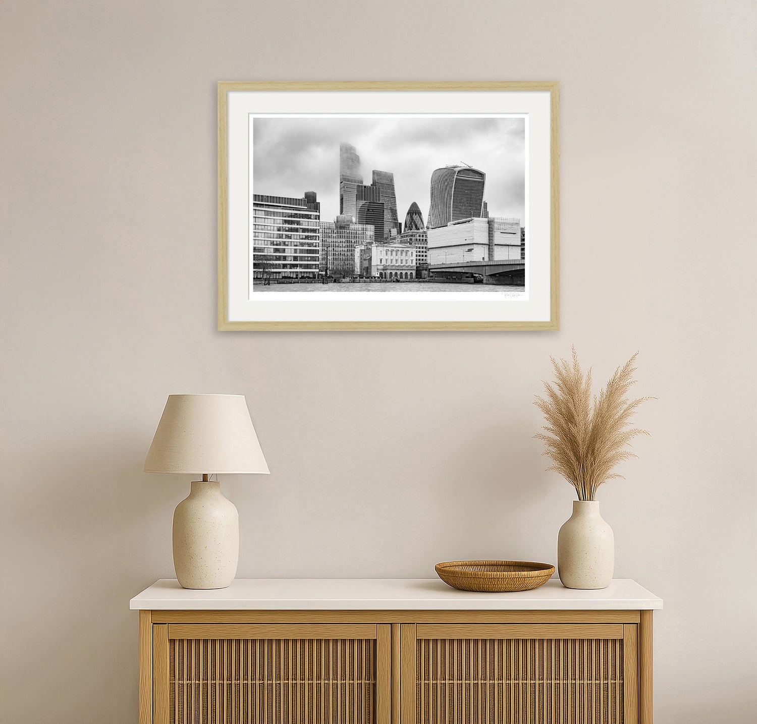 Minimalist living room with black and white framed London skyline art above a wooden sideboard
