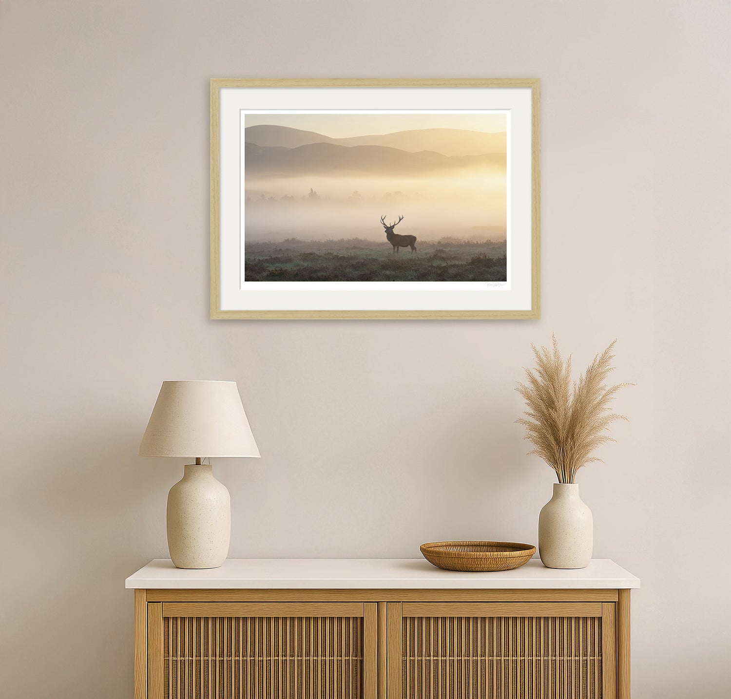 Natural wood framed deer print hanging in a warm-toned modern living room with natural light and rustic decor.