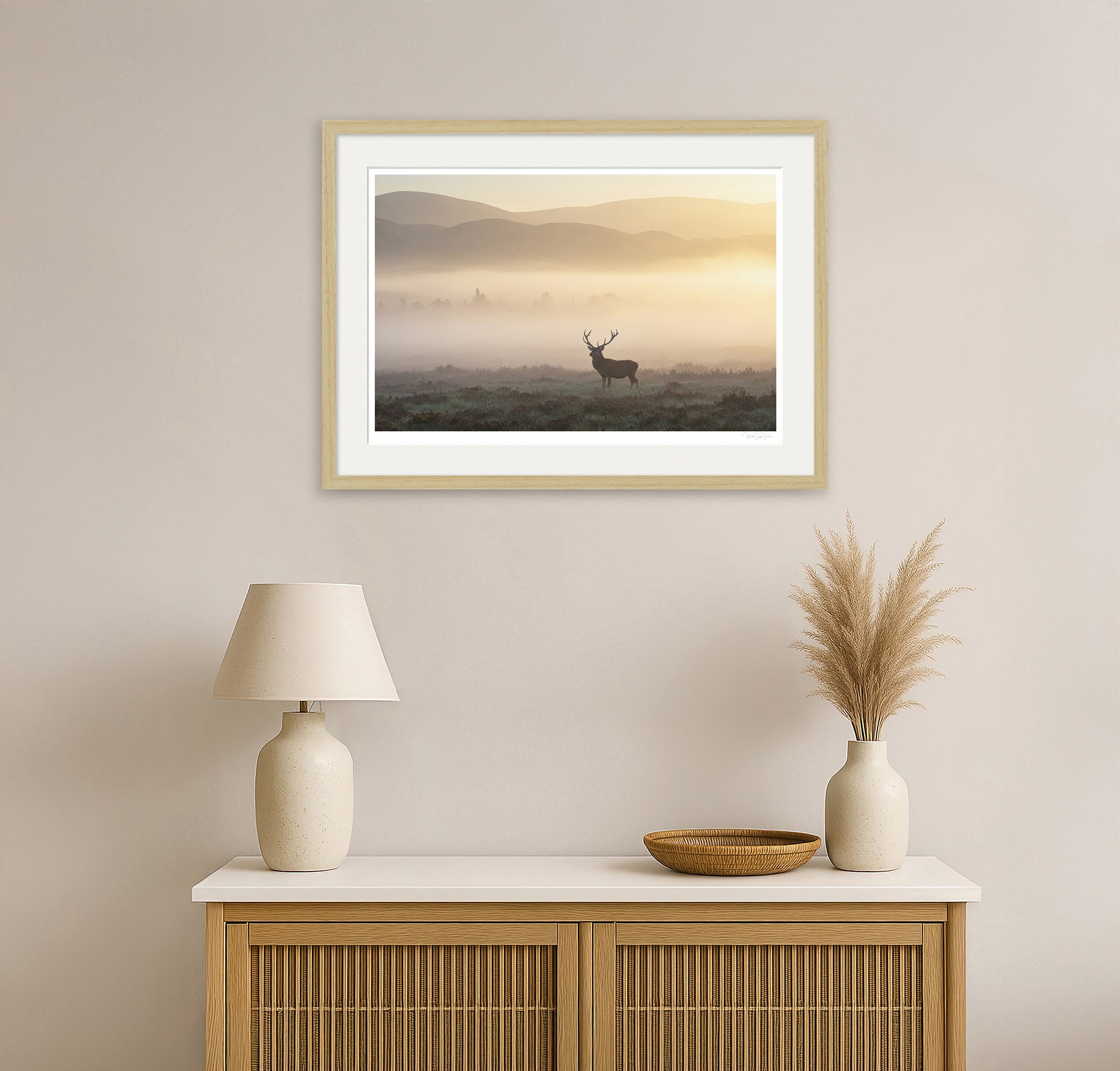 Natural wood framed deer print hanging in a warm-toned modern living room with natural light and rustic decor.