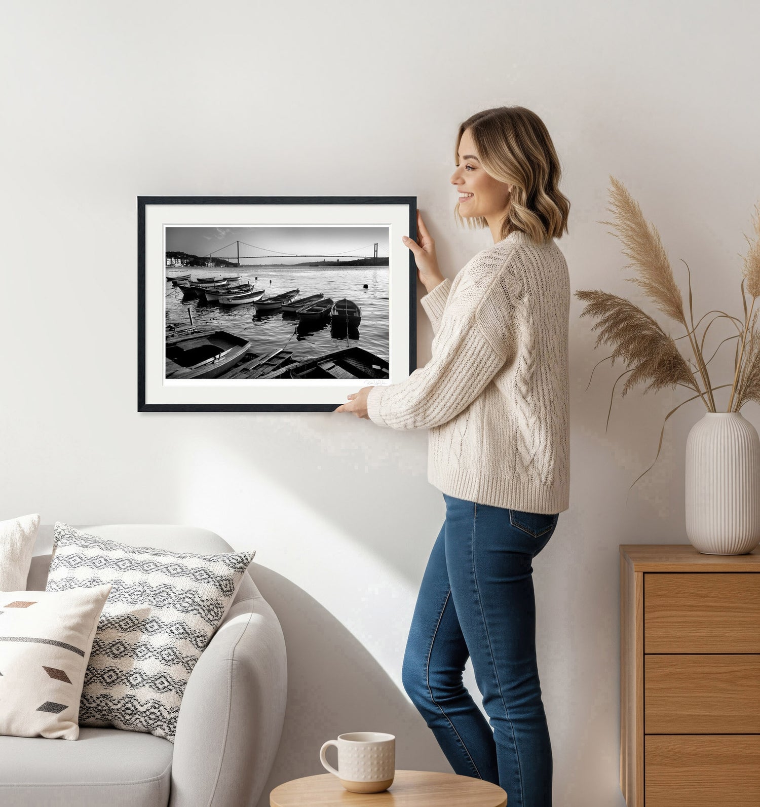 Woman hanging framed black and white Istanbul Bosphorus print on wall – minimalist home decor scene