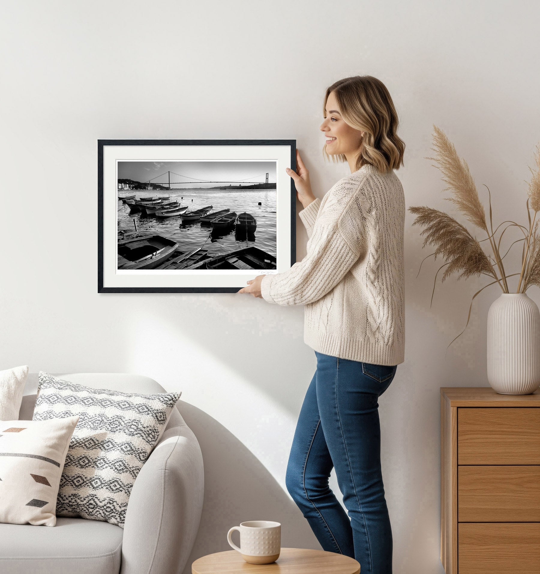 Woman hanging framed black and white Istanbul Bosphorus print on wall – minimalist home decor scene