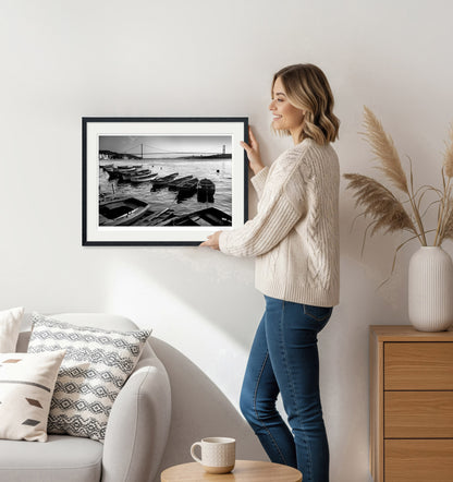 Woman hanging framed black and white Istanbul Bosphorus print on wall – minimalist home decor scene