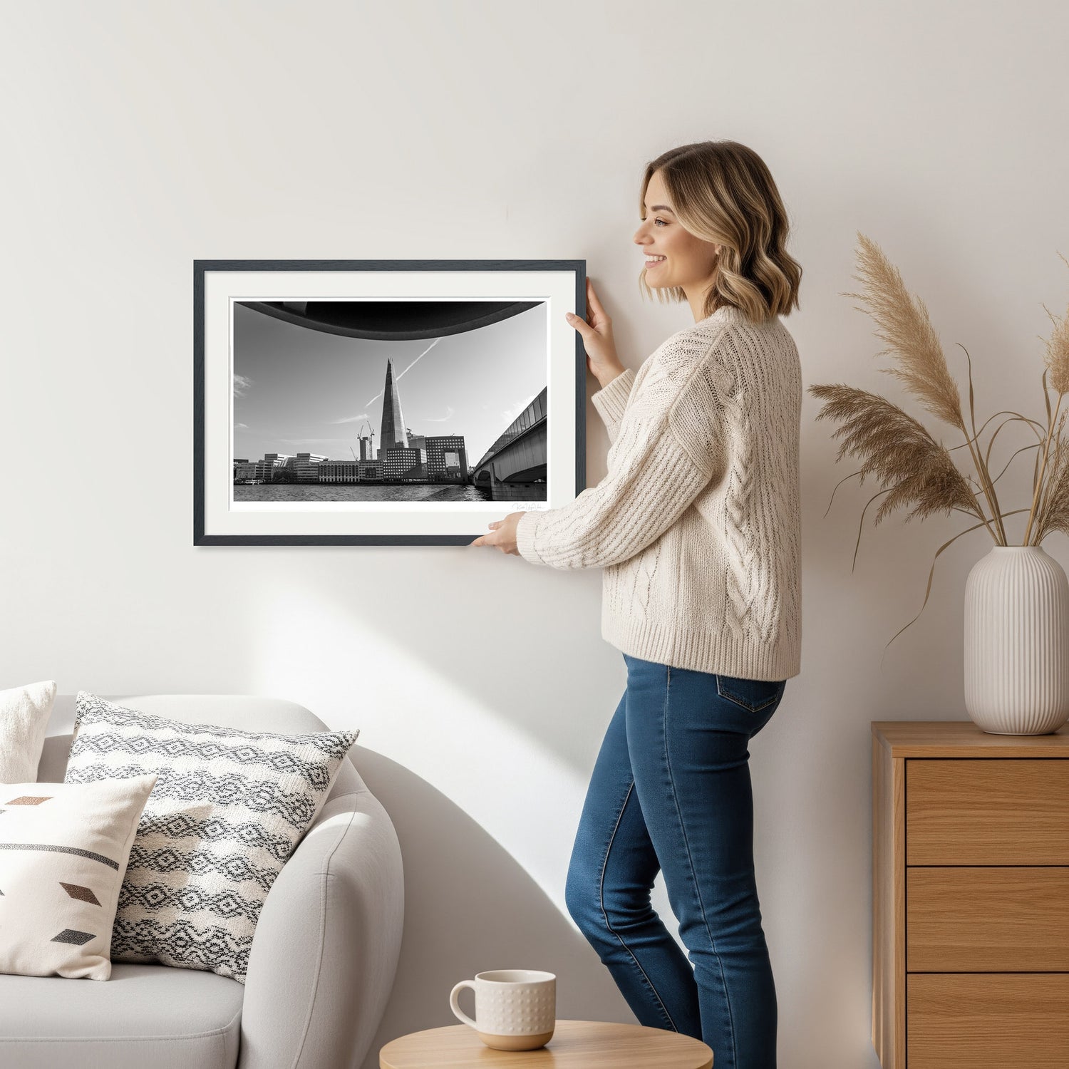 Woman holding framed black and white photo print of The Shard in London, ideal for wall art decor in modern interiors.
