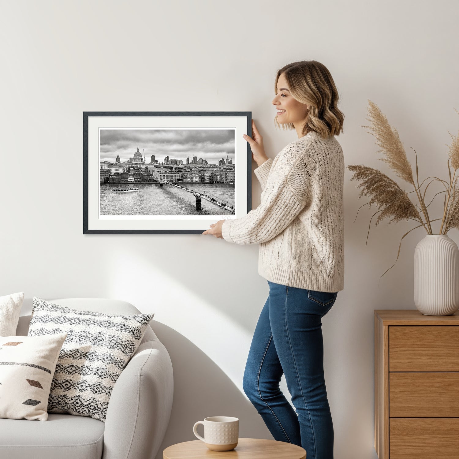 Woman holding framed black and white London art print showing Millennium Bridge and St. Paul’s Cathedral