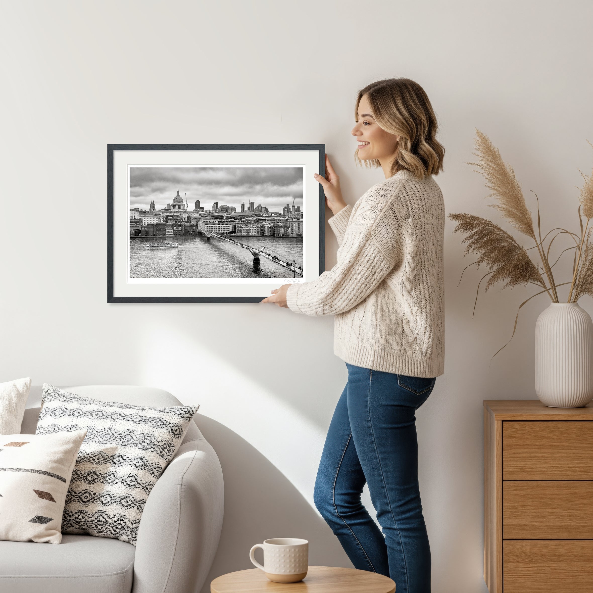 Woman holding framed black and white London art print showing Millennium Bridge and St. Paul’s Cathedral
