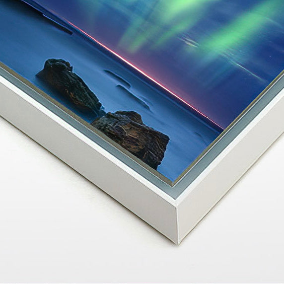 Close-up of a sleek white Aluminium Artbox framing a colorful aurora landscape print.